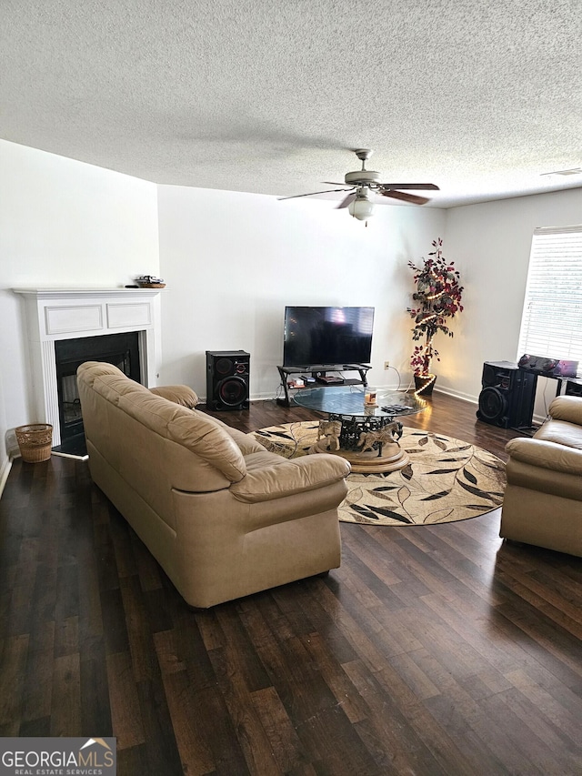 living room with a textured ceiling, ceiling fan, and dark wood-type flooring