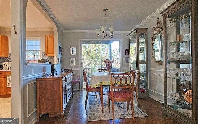 tiled dining area featuring a chandelier, ornamental molding, and a healthy amount of sunlight