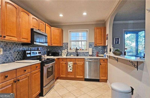 kitchen featuring backsplash, sink, ornamental molding, light tile patterned floors, and stainless steel appliances