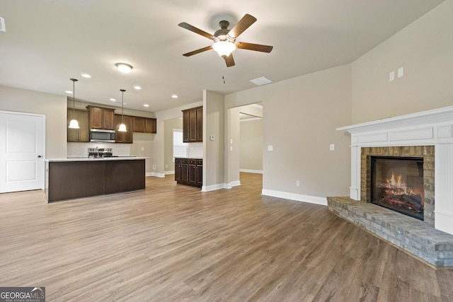 unfurnished living room featuring ceiling fan, a fireplace, and wood-type flooring