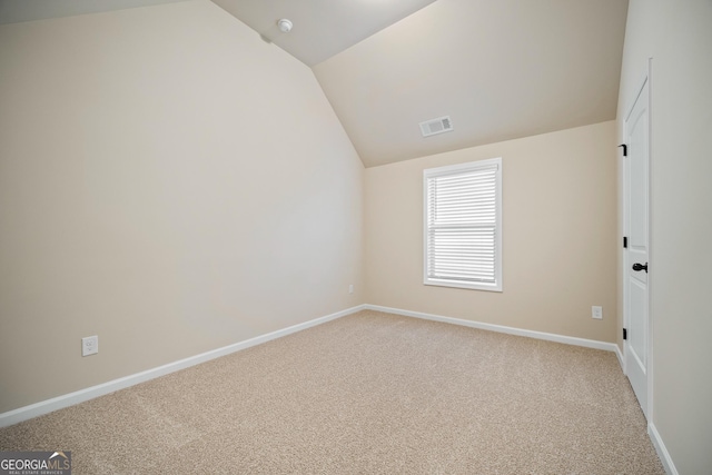 carpeted spare room with lofted ceiling