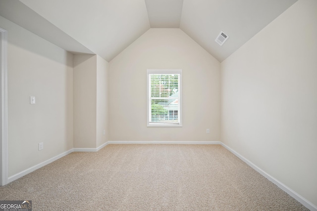 carpeted spare room with lofted ceiling