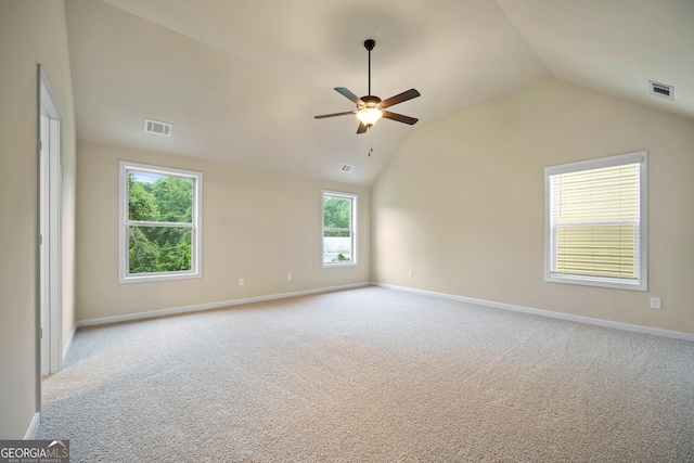 spare room with a wealth of natural light, ceiling fan, light colored carpet, and lofted ceiling