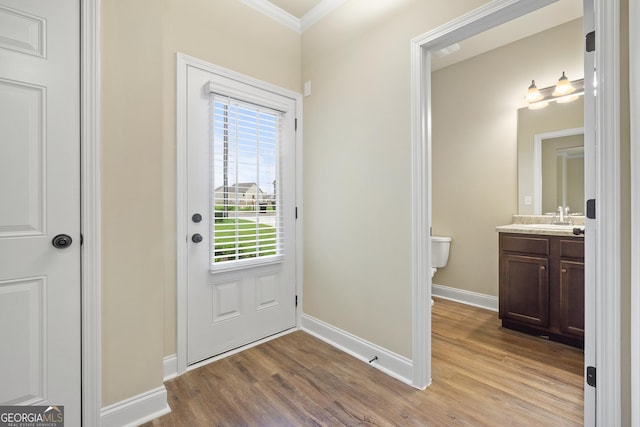 entryway with crown molding, light hardwood / wood-style flooring, and sink