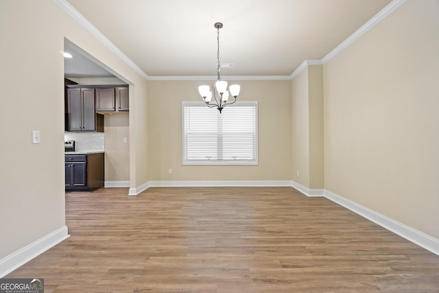 unfurnished dining area with light hardwood / wood-style floors, an inviting chandelier, and ornamental molding