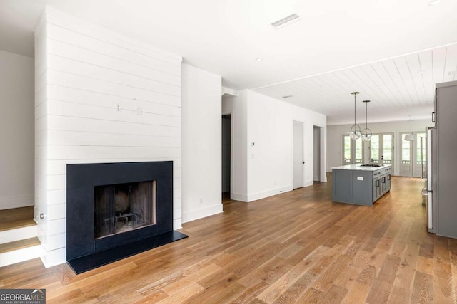 unfurnished living room with light wood-type flooring and a large fireplace