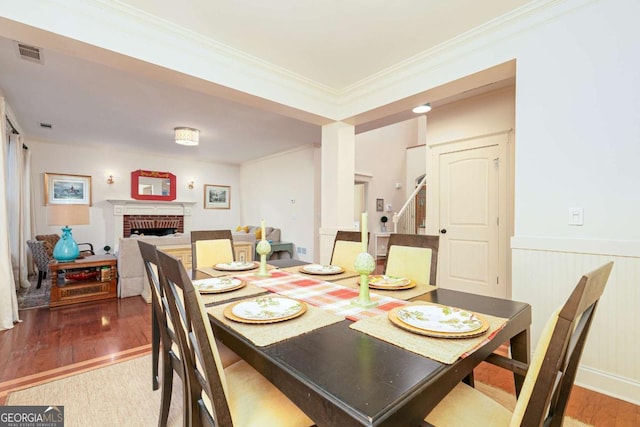 dining room featuring a brick fireplace, hardwood / wood-style floors, and ornamental molding