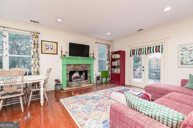 living room with crown molding, a healthy amount of sunlight, and a stone fireplace