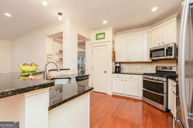 kitchen with stainless steel appliances, kitchen peninsula, dark stone counters, sink, and tasteful backsplash