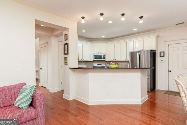 kitchen featuring ornamental molding, stainless steel appliances, white cabinetry, and decorative backsplash