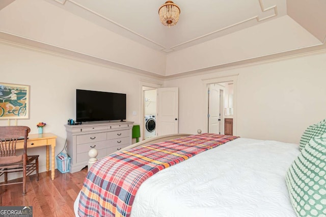 bedroom featuring hardwood / wood-style floors, washer / clothes dryer, and a tray ceiling