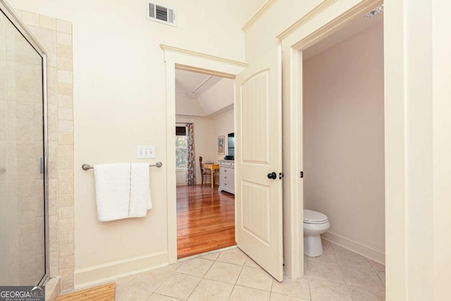 bathroom with toilet, tile patterned flooring, a shower with shower door, and lofted ceiling