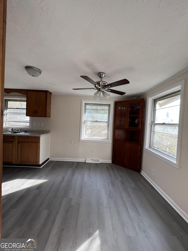 unfurnished living room featuring hardwood / wood-style floors, a healthy amount of sunlight, and a textured ceiling