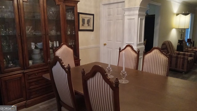 dining space with dark wood-type flooring and decorative columns