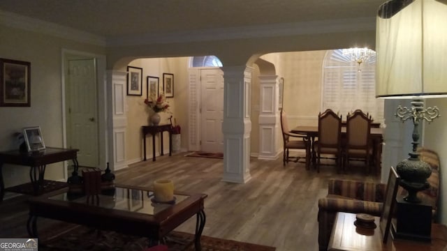 interior space featuring decorative columns, wood-type flooring, and crown molding