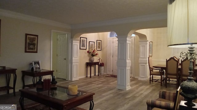 living room with crown molding, hardwood / wood-style floors, and ornate columns