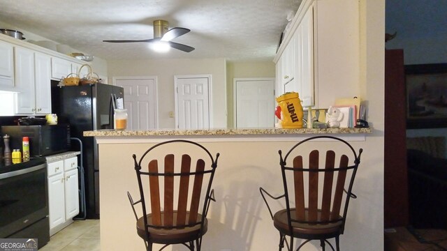 kitchen featuring white cabinetry, light stone counters, kitchen peninsula, and a breakfast bar