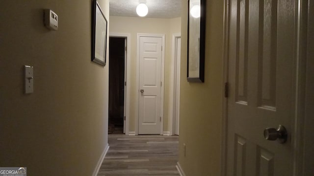 hall with hardwood / wood-style floors and a textured ceiling