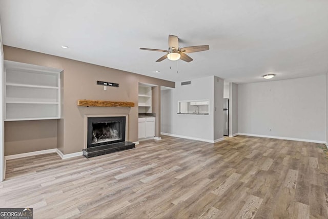 unfurnished living room with ceiling fan and light wood-type flooring