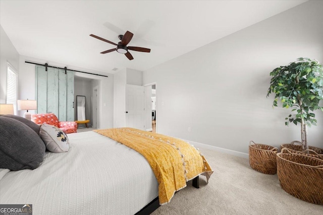 carpeted bedroom with ceiling fan and a barn door