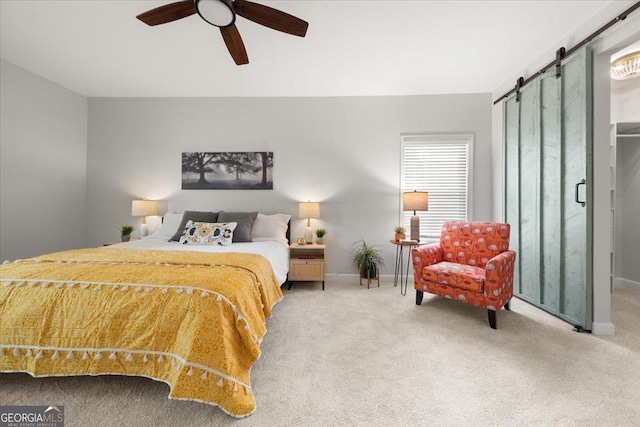 bedroom featuring a barn door, carpet floors, and ceiling fan