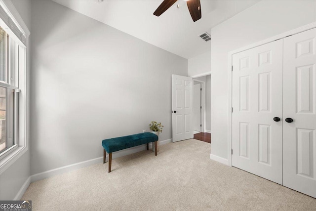 living area with light carpet and ceiling fan