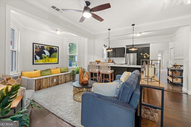 living room with crown molding, ceiling fan, and dark wood-type flooring