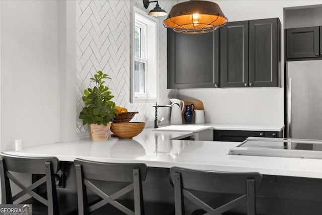 kitchen featuring stainless steel fridge, sink, and a breakfast bar area