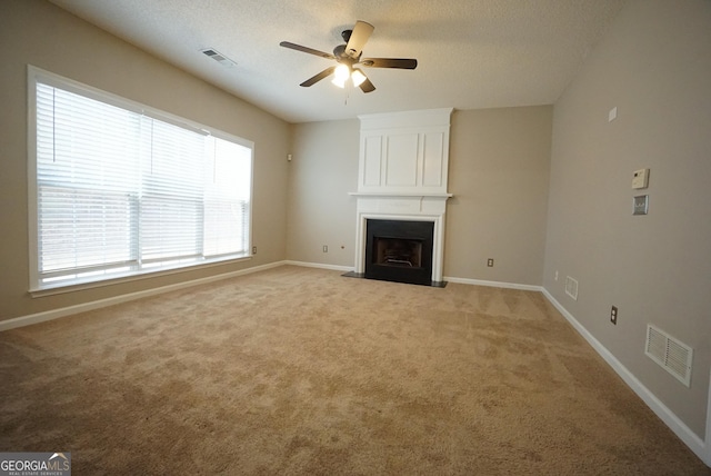 unfurnished living room featuring a large fireplace, baseboards, visible vents, and light colored carpet