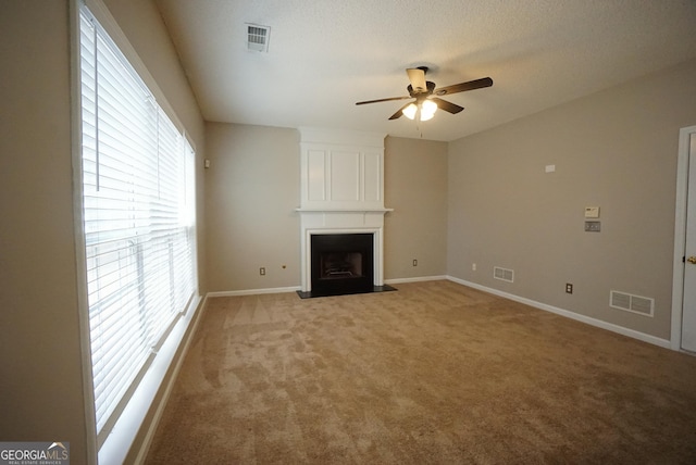 unfurnished living room with a ceiling fan, a fireplace, visible vents, and light colored carpet