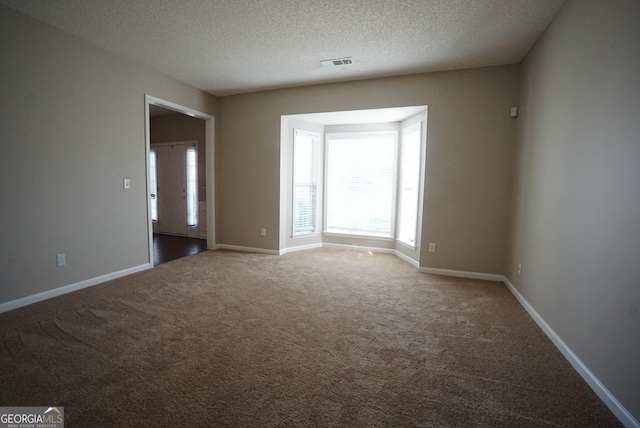 carpeted empty room with a textured ceiling, visible vents, and baseboards