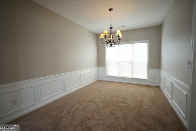 empty room featuring a decorative wall, light colored carpet, a notable chandelier, visible vents, and wainscoting