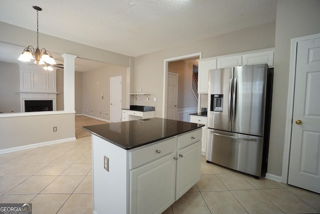 kitchen featuring stainless steel refrigerator with ice dispenser, light tile patterned floors, dark countertops, white cabinetry, and a chandelier