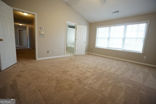 unfurnished bedroom with baseboards, visible vents, lofted ceiling, ensuite bathroom, and carpet flooring