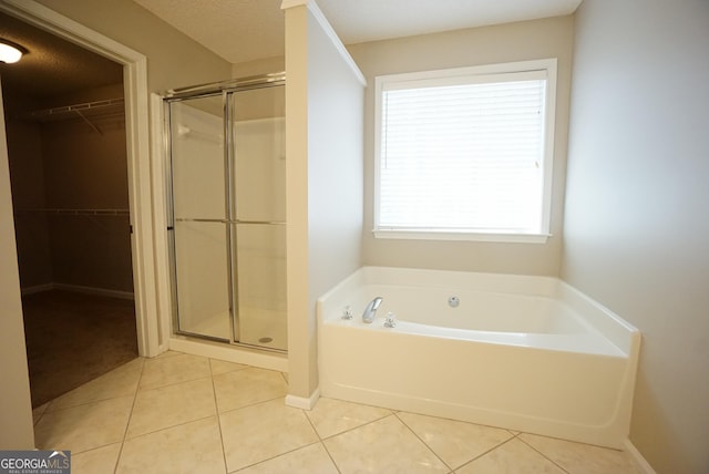 bathroom with a stall shower, baseboards, tile patterned flooring, a walk in closet, and a bath