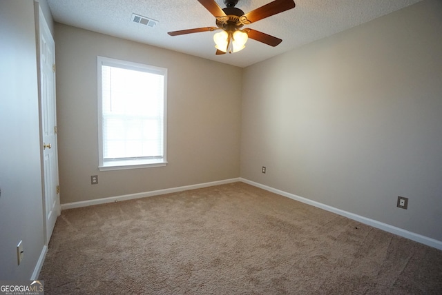 carpeted spare room featuring a textured ceiling, a ceiling fan, visible vents, and baseboards