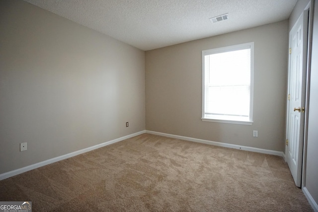 unfurnished room featuring carpet floors, baseboards, visible vents, and a textured ceiling