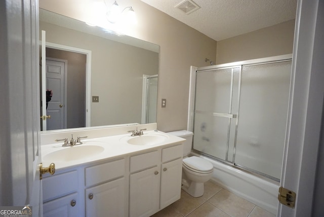 full bath with toilet, tile patterned flooring, a textured ceiling, and a sink