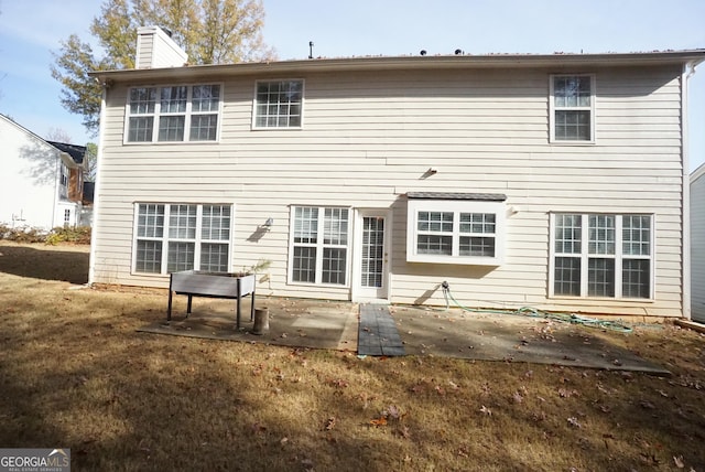 back of house with a patio, a yard, and a chimney