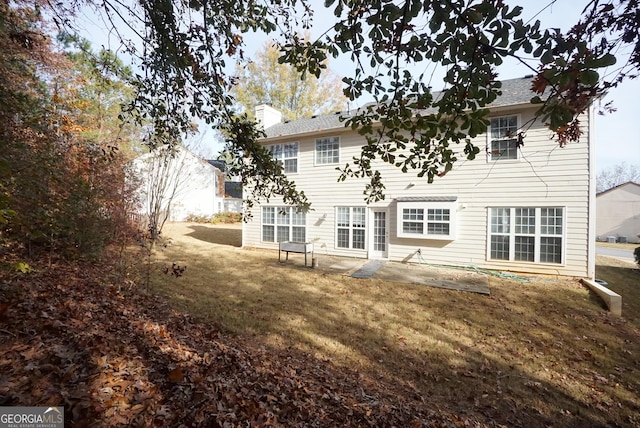 rear view of house featuring a chimney and a lawn