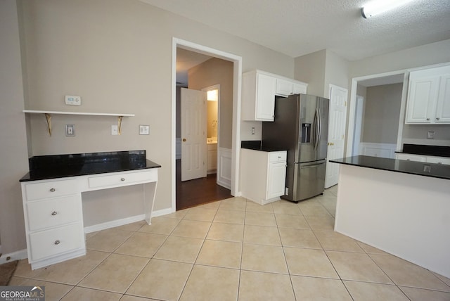 kitchen with dark countertops, white cabinetry, light tile patterned flooring, and stainless steel fridge with ice dispenser