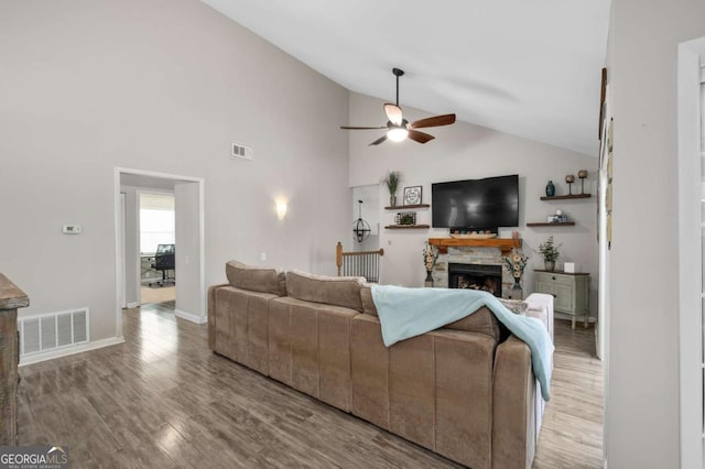 living room featuring hardwood / wood-style floors, ceiling fan, a fireplace, and high vaulted ceiling