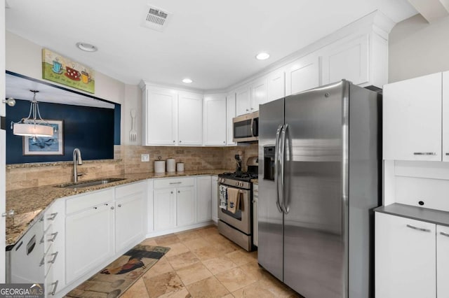 kitchen with white cabinetry, sink, hanging light fixtures, backsplash, and appliances with stainless steel finishes