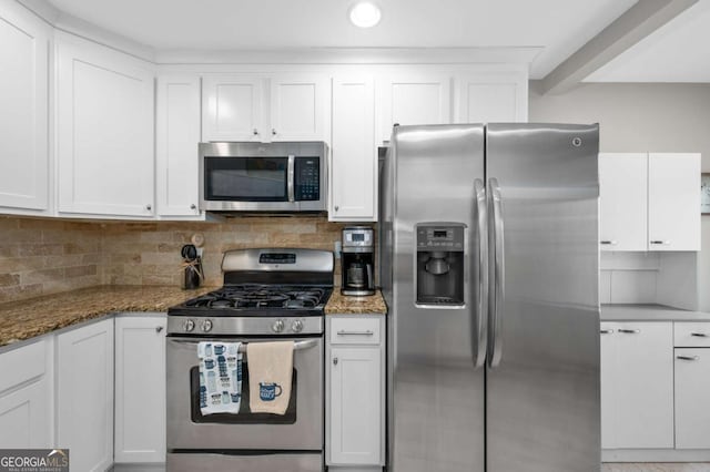 kitchen with dark stone counters, backsplash, white cabinetry, and stainless steel appliances