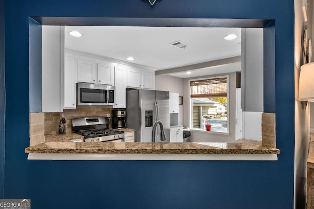 kitchen with white cabinets, backsplash, stainless steel appliances, and light stone counters