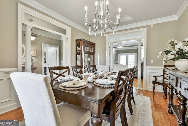 dining area with decorative columns, light hardwood / wood-style flooring, ceiling fan with notable chandelier, and ornamental molding