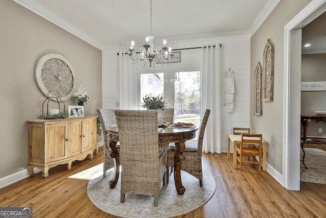 dining space with light wood-type flooring, crown molding, and a notable chandelier