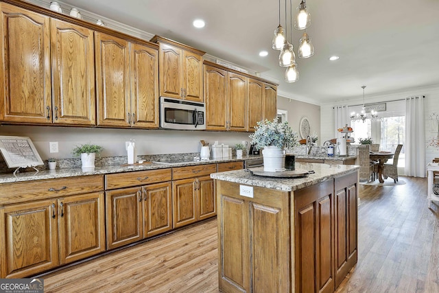 kitchen with light hardwood / wood-style flooring, a chandelier, pendant lighting, appliances with stainless steel finishes, and ornamental molding