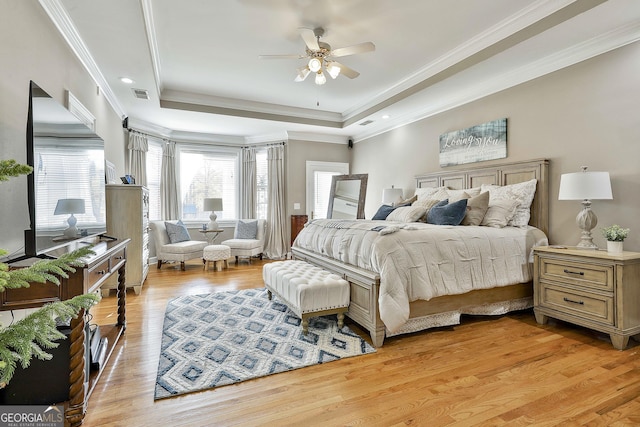 bedroom with a raised ceiling, ceiling fan, and light wood-type flooring