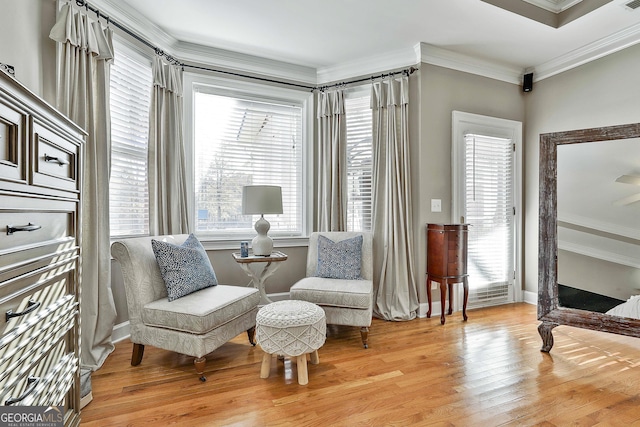 sitting room featuring ornamental molding and light wood-type flooring